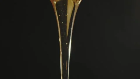 Thin stream of liquid floral honey on black background in studio. Stock Footage 309952040