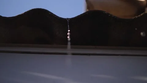 A thin stream of melt water drips from the roof slate. drops of water Stock Footage 147089818