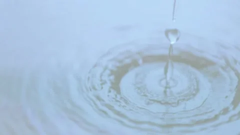 Thin stream narrowing, making droplets form, fall, splash and create ripples to Stock Footage 332472865