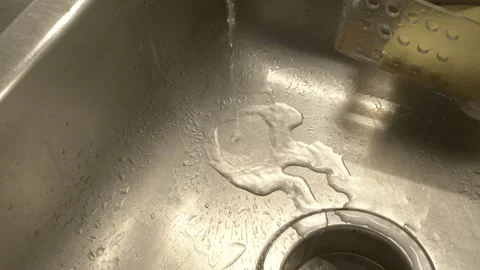 Thin stream of Tap water going down on a silver sink graded and raw 스톡 동영상 158455604