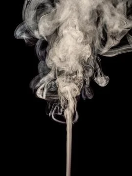 A thin stream of white smoke curls and rising up isolated on a black Stock Photos
