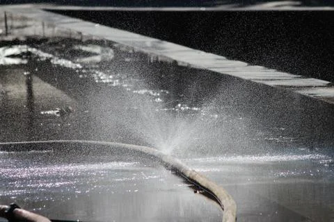 Thin streams of water from the hose in front of the sunlight in the spring. Foto stock