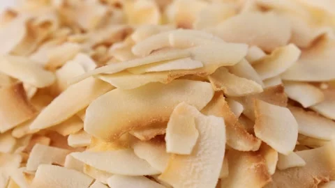 Thin sweet toasted coconut chips falling down close up Stock Footage 274906179