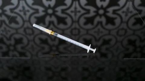 Thin syringe slowly falls on a dark surface. Concept of insulin dependence 動画素材 262335664