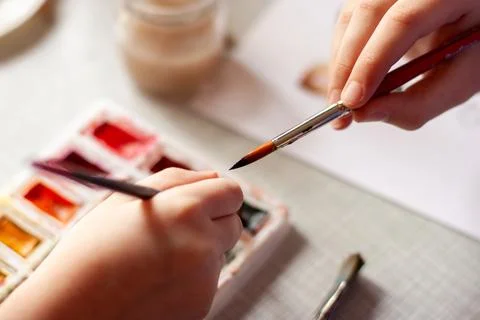 The thin tip of the brush, two children's hands, watercolor paints Stock Photos