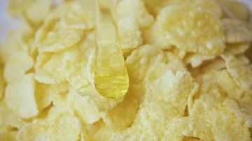 A thin trickle of honey pours on the flakes slow mo Stock Footage 85473099