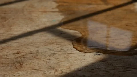 Thin water stream trickling across rustic aged wood grain surface Видео 336665455