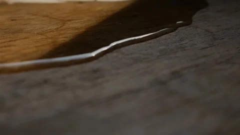 Thin water stream trickling across rustic aged wood grain surface Vidéo 336665495