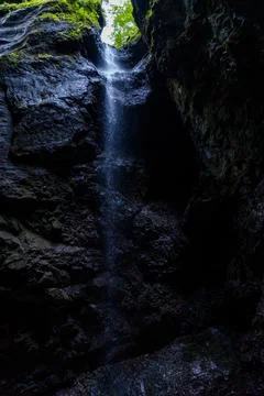 Thin Waterfall Dripping Down Dark Gorge Stock Photos