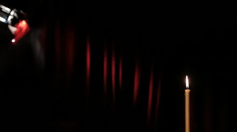 Thin wax candle is lit and burning on a black background with a red beam Stock Footage 46953224