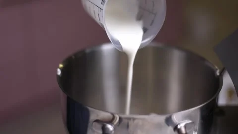 A thin white stream flows out of the beaker into an iron pan Vidéo 275146152