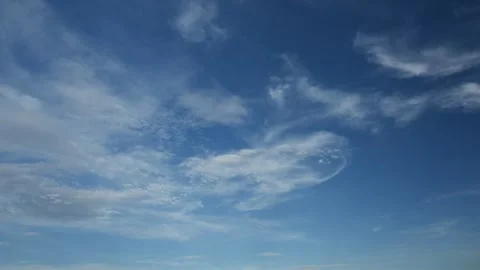 Thin white summer clouds drifting through a blue sky away from the viewer Stock Footage 311128649