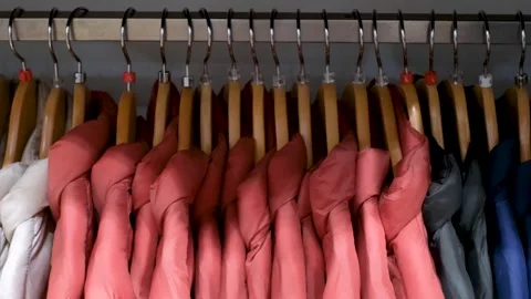 Thin winter multi-colored jackets on hangers, side view. Stock Footage 322552554