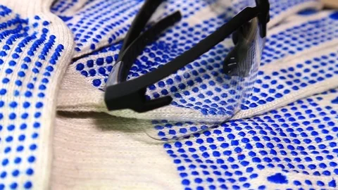 Thin work gloves with  blue pimples, protective glasses  on a rotating surface Stock Footage 70826382