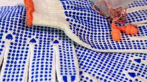 Thin work gloves with  blue pimples, and ear plugs on a rotating surface Stock-Footage 70826439