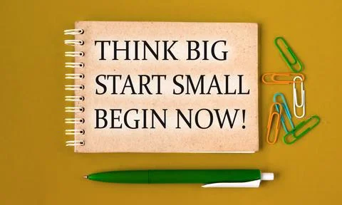 THINK BIG START SMALL BEGIN NOW! - words on a gray notebook with pen and pa.. Stock Photos