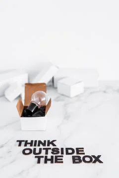 Think outside the box concept with idea lightbulb on top of white box and tex Stock Photos