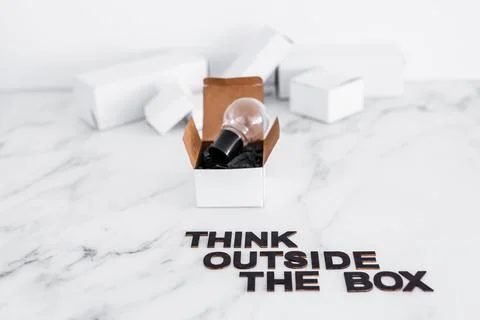 Think outside the box concept with idea lightbulb on top of white box and tex Stock Photos