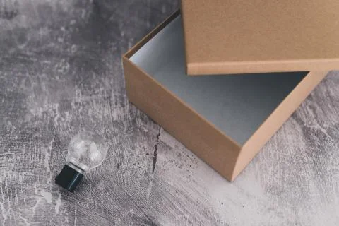Think outside the box empty container with one lightbulb outside of it Stock Photos
