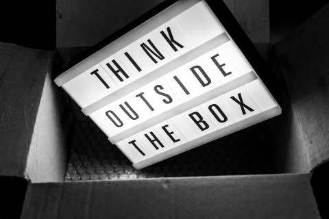 Think outside the box message on lightbox coming out of a parcel Stockfoto's