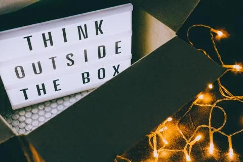 Think outside the box message on lightbox coming out of a parcel with fairy l Foto stock