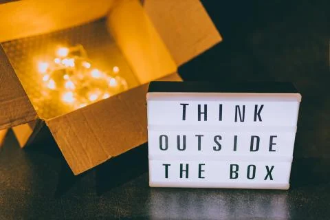 Think outside the box message on lightbox next to open parcel with fairy led  Stock Photos