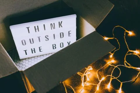 Think outside the box message on lightbox coming out of a parcel with fairy l Stock Photos