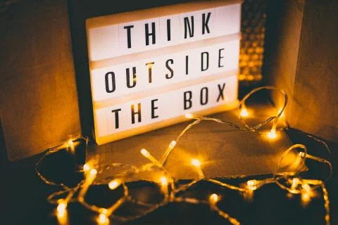 Think outside the box message on lightbox next to open parcel with fairy led  写真素材