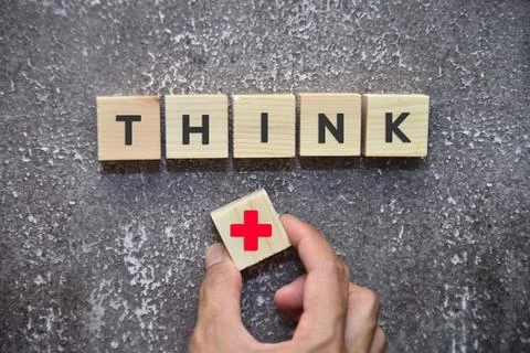 THINK text on the wood blocks with hand holding wood block with POSITIVE symbol Stock Photos