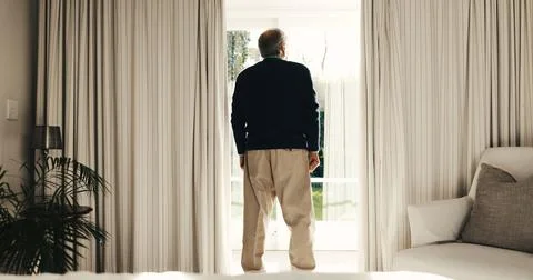 Thinking, back and senior man by window in home, perspective and ponder in Fotos de archivo
