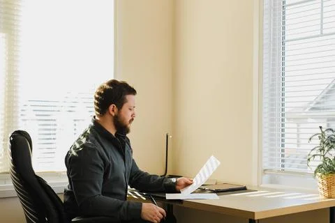 Thinking broker sitting at office with documents, tablet on table. 스톡 사진