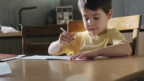 Thinking child sitting at table studying at home doing school homework. Writing Stock Footage 170872010