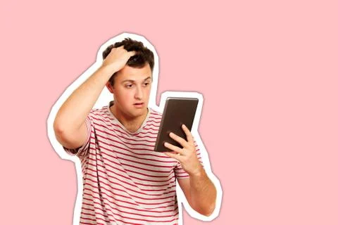 Thinking guy looks at the tablet and scratches his head with his hand. emotio Fotos de archivo