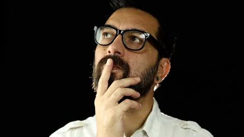 Thinking man with beard and glasses on black background. Stock Footage 157500857
