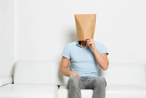 Thinking man with face covered sitting on couch. Stock-Fotos