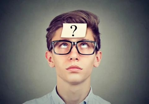 Thinking man with question mark looking up on gray wall background Stock Photos