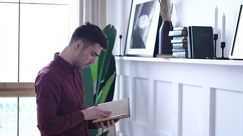 Thinking man reading book in home library on bookcase background. Stock Footage 105341390