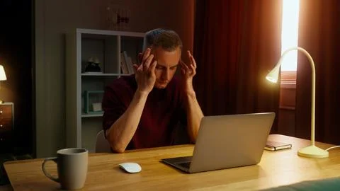 Thinking man work at home with laptop suffer headache. Guy feel bad, head pai Stock Photos