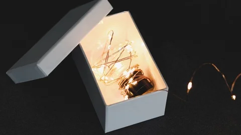 Thinking outside the box, idea lightbulb wrapped up in string lights shining  Stock Footage 118357220