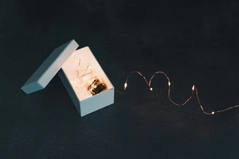 Thinking outside the box, idea lightbulb wrapped up in string lights shinging Stock Photos