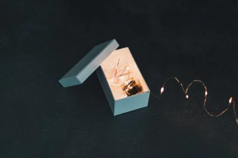 Thinking outside the box, idea lightbulb wrapped up in string lights shinging Stock Photos