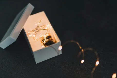 Thinking outside the box, idea lightbulb wrapped up in string lights shinging Stock Photos