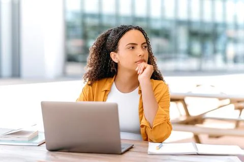 Thinking over idea, planning. Pensive brazilian or hispanic curly haired girl Foto stock