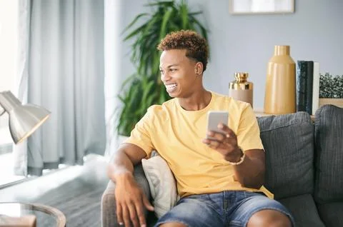 Thinking, phone and man on sofa in home with networking, communication or social Stock Photos