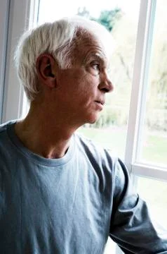 Thinking senior man looking through a window Stock Photos