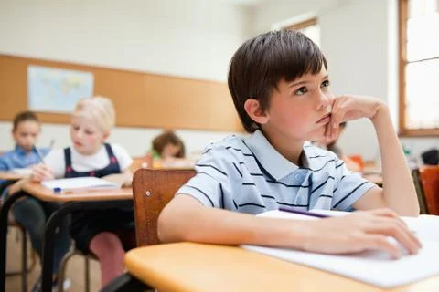 Thinking student sitting at his desk 库存照片