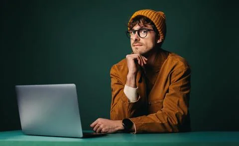 Thinking through work, the man uses a laptop in a studio workspace Stock Photos