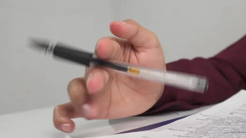 Thinking while fiddling or playing with a pen on table 库存影片 277316513