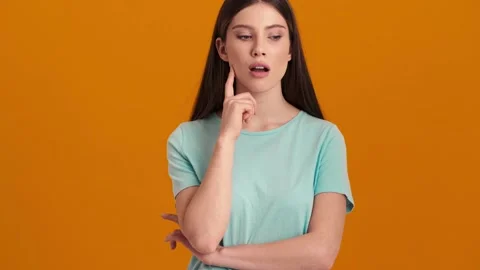 A thinking woman wearing basic T-shirt coming-up with idea in the orange studio Video stock 154316504