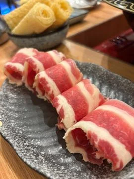 Thinly-shaved beef, beautifully rolled and presented on a dark gray Stock Photos